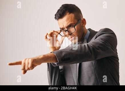 un jeune homme d'affaires regarde quelque chose de sous ses verres et pointe son doigt Banque D'Images