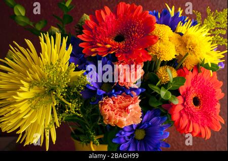 Fleurs multicolores, y compris mamans, chrysanthèmes, œillets dans un seau jaune Banque D'Images