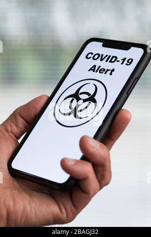 Homme tenant le téléphone portable avec l'alerte COVID-19 à l'écran Banque D'Images