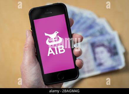 Une femme regardant le logo de la banque irlandaise alliée sur un téléphone mobile. (Usage éditorial uniquement) Banque D'Images