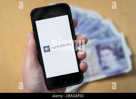 Une femme regardant le logo Alpha Bank sur un téléphone mobile. (Usage éditorial uniquement) Banque D'Images