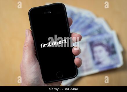 Une femme regardant le logo First Direct Bank sur un téléphone mobile. (Usage éditorial uniquement) Banque D'Images