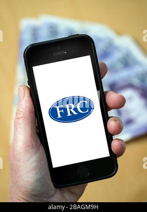 Une femme qui regarde le logo du Financial Reporting Council sur un téléphone mobile. (Usage éditorial uniquement) Banque D'Images