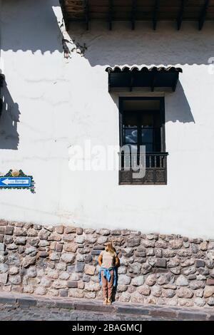 Une jeune femme se tient près d'un mur blanc à Cusco, au Pérou Banque D'Images