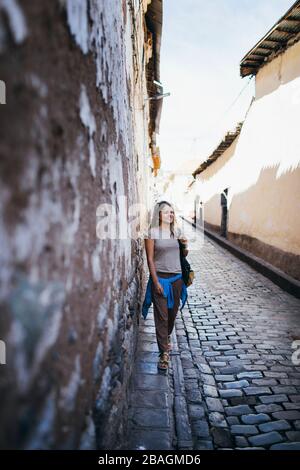 Une jeune femme se tient près d'un vieux mur à Cusco, au Pérou Banque D'Images