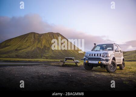 4x4 stationné à côté de la table de pique-nique devant la montagne, à côté de la rivière Banque D'Images