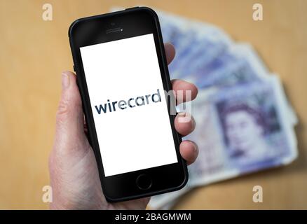 Une femme regardant le logo de la société de services financiers de Wirecard sur un téléphone mobile. (Usage éditorial uniquement) Banque D'Images