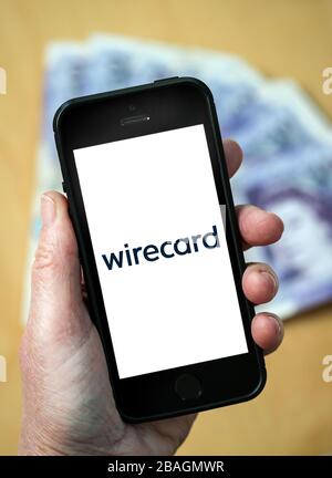 Une femme regardant le logo de la société de services financiers de Wirecard sur un téléphone mobile. (Usage éditorial uniquement) Banque D'Images