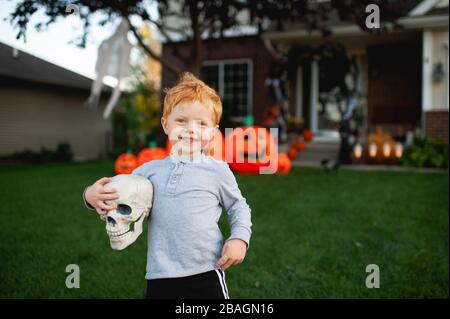 Un tout-petit souriant en tenant le décor d'halloween dans la cour avant Banque D'Images