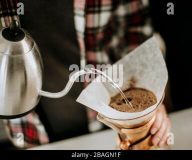 l'eau chaude est versée de la bouilloire à la mouture de café dans un filtre. Banque D'Images