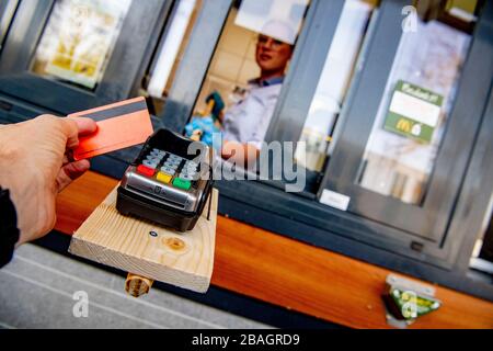 Un employé du restaurant McDonald's a été vu passer une machine de carte de paiement à l'aide d'un dispositif d'extension libre de contact auto-conçu pour maintenir la distance sociale recommandée de 1,5 mètre avec le client. En raison de l'épidémie de coronavirus COVID-19, Les restaurants McDonald's aux Pays-Bas ont recommandé au personnel de conserver une distance sociale recommandée de 1,5 mètre de ses clients. Les restaurants acceptent uniquement les paiements par carte sans fil et la nourriture doit être laissée sur un comptoir de prise en charge pour les clients que les membres du personnel ont quitté la zone afin de minimiser le chan Banque D'Images