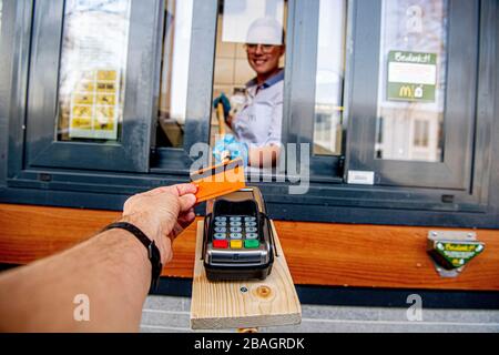 Un employé du restaurant McDonald's a été vu passer une machine de carte de paiement à l'aide d'un dispositif d'extension libre de contact auto-conçu pour maintenir la distance sociale recommandée de 1,5 mètre avec le client. En raison de l'épidémie de coronavirus COVID-19, Les restaurants McDonald's aux Pays-Bas ont recommandé au personnel de conserver une distance sociale recommandée de 1,5 mètre de ses clients. Les restaurants acceptent uniquement les paiements par carte sans fil et la nourriture doit être laissée sur un comptoir de prise en charge pour les clients que les membres du personnel ont quitté la zone afin de minimiser le chan Banque D'Images