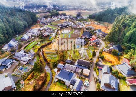 Petites fermes agricoles avec rizières, serres sur les rives de la petite rivière de montagne dans le village japonais. Banque D'Images