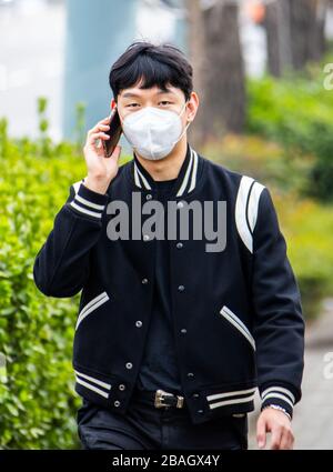 Jeune homme sur son téléphone portable portant un masque de protection pendant la pandémie de Coronavirus, Séoul, Corée Banque D'Images