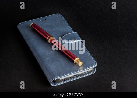 IPhone avec étui et stylo rouge sur fond noir Banque D'Images