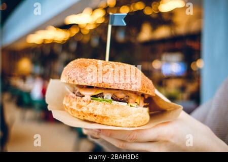 Fille tient un hamburger sur le fond du restaurant. Gros plan. Banque D'Images