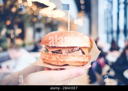 Fille tient un hamburger sur le fond du restaurant. Tons. Gros plan. Banque D'Images