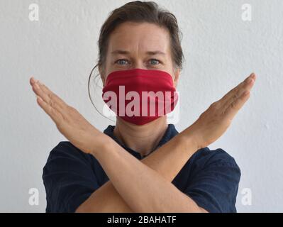 Femme caucasienne pose pour l'appareil photo avec son masque de visage de bricolage (fabriqué à partir d'une vieille pochette de t-shirt) pendant la pandémie de corona-virus 2019/20. Banque D'Images
