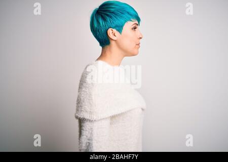 Jeune femme belle avec des cheveux de mode bleu portant un pull décontracté sur fond blanc regardant sur le côté, se détendre profil pose avec le visage naturel avec c Banque D'Images