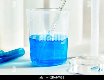 Liquide bleu avec un verre incorporer un bécher avec des tubes à essai et un plat de Petri avec peu de profondeur de champ Banque D'Images