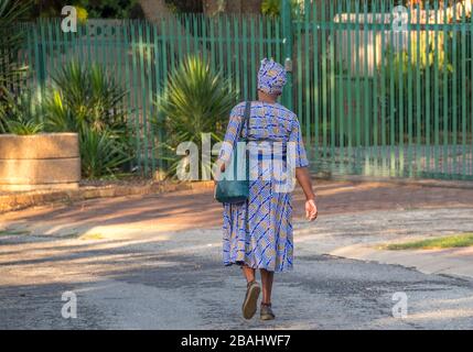 Alberton, Afrique du Sud : une femme africaine noire, bien habillée et non identifiée, marche dans une rue dans un quartier résidentiel Banque D'Images