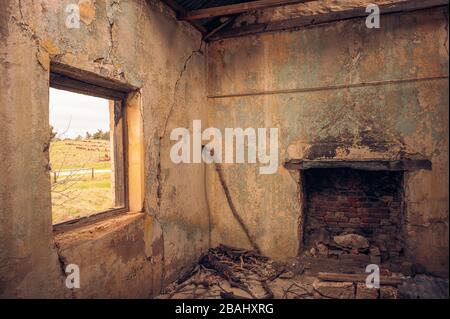 La salle de séjour d'un ancien bâtiment abandonné avec un jeune colon qui regarde la cheminée et la fenêtre ouverte donnant sur la vallée dans la chaîne des Flinders. Banque D'Images