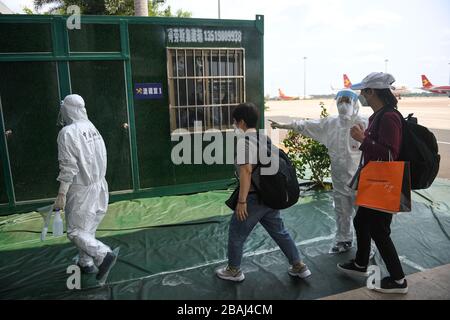 Haikou, province de Hainan en Chine. 27 mars 2020. Un membre du personnel des douanes de l'aéroport international de Meilan conduit les passagers à mener une enquête épidémiologique à Haikou, dans la province de Hainan, en Chine méridionale, le 27 mars 2020. Ces derniers jours, l'aéroport international de Meilan a pris des mesures strictes, y compris le dépistage de la température corporelle à deux reprises, l'inspection médicale, l'enquête épidémiologique et le test des échantillons, afin de minimiser les risques de cas importés de COVID-19. Crédit: Pu Xiaoxu/Xinhua/Alay Live News Banque D'Images