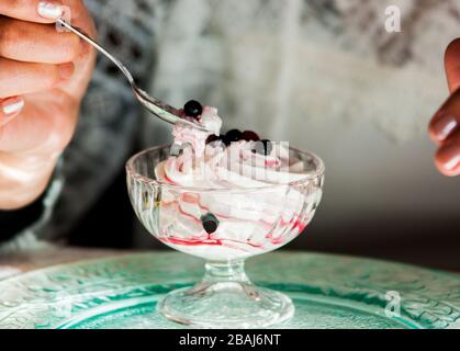 verre de crème fouettée blanche pure avec sirop doux et baies rouges juteuses Banque D'Images