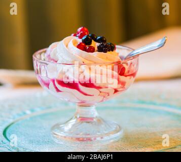 verre de crème fouettée blanche pure avec sirop doux et baies rouges juteuses Banque D'Images