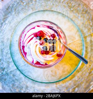 verre de crème fouettée blanche pure avec sirop doux et baies rouges juteuses Banque D'Images