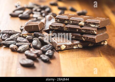 Barres de chocolat au lait et fèves de cacao sur table en bois Banque D'Images