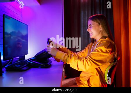 gamer fille jouant à la course sur un ordinateur. Elle utilise un volant. Jeu émotionnel Banque D'Images