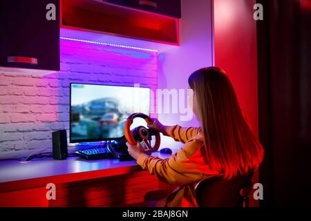 gamer fille jouant à la course sur un ordinateur. Elle utilise un volant. Jeu émotionnel Banque D'Images