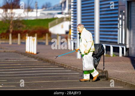 Glasgow, Écosse. 28 mars 2020. Une figure solitaire de collecte d'autres peuples ordures dans un parc de détail déserté Colin Poultney / Alay Live News Banque D'Images