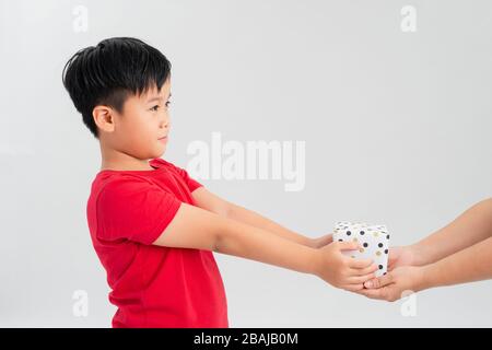 Portrait of a happy cute little kid holding gift box and looking at camera isolated over white background Banque D'Images