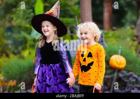 Enfant en costume d'Halloween. Les enfants font des trucs ou des friandises. Petit garçon et fille vêtu de sorcière avec chapeau tenant lanterne de citrouille et seau de bonbons. Célébrité de la famille Banque D'Images