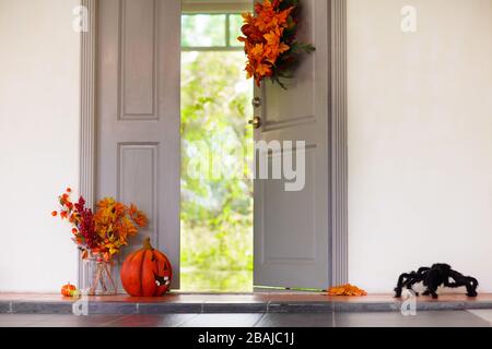 Entrée maison décorée pour Halloween. Lanterne à citrouille et feuilles d'automne à la porte d'entrée de la maison. Décoration orange et noire. Intérieur prêt pour le tour ou Banque D'Images