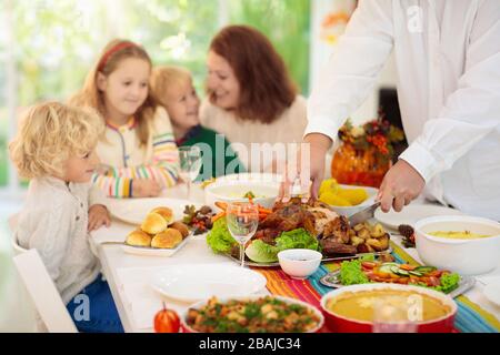 Famille avec enfants mangeant le dîner de Thanksgiving. dinde rôtie et tarte à la citrouille sur la table à manger avec décoration d'automne. Les parents et les enfants ayant des fpris Banque D'Images