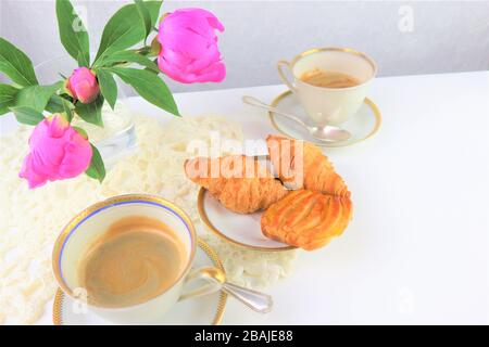 Le petit-déjeuner avec deux tasses de café et croissants, bouquet de fleurs roses pivoines Banque D'Images