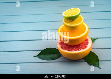 sur une table en bois bleu se trouve une coupe de pamplemousse, sur le dessus est orange, citron et citron vert. citrons juteux et appétissants. fond. Banque D'Images