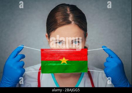 Coronavirus au Burkina Faso Portrait de docteur féminin protège le masque médical chirurgical du visage avec le drapeau national du Burkina Faso. Maladie, virus Covid-19 po Banque D'Images