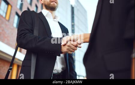 Poignée de main. Homme d'affaires et femme d'affaires font des poignées tout en se tenant à l'extérieur dans un bâtiment d'affaires. Banque D'Images