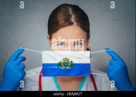 Coronavirus à Saint-Marin Doctor féminin Portrait tenir protéger le masque médical chirurgical visage avec le drapeau national de Saint-Marin. Maladie, virus Covid-19 à San Banque D'Images