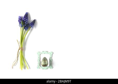 Bouquet de fleurs de printemps bleues avec oeuf de Pâques dans un cadre sur fond blanc. Symbole de Pâques, célébration. Banque D'Images