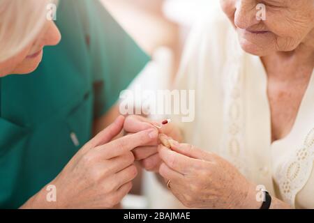 Femme médecin appliquant une aide auditive à l'oreille d'une femme âgée Banque D'Images