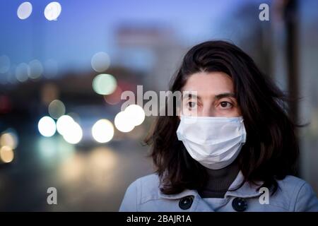 Une femme portant un masque facial et se tenant à l'extérieur pendant l'éclosion de Coronavirus Banque D'Images