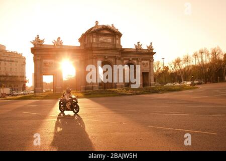 Madrid, Espagne - Motorcycliste passant devant la lumière du soleil à Puerta de Alcala sur la Plaza de la Independencia. Banque D'Images