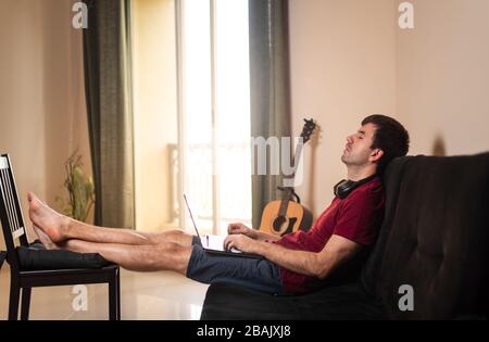 Homme prenant la sieste tout en travaillant de la maison dans le canapé Banque D'Images