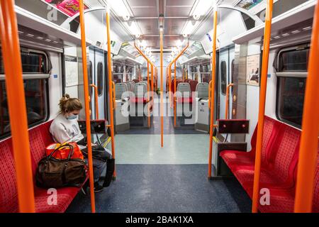 Une femme portant un masque chirurgical sur un train terrestre londonien alors que les navetteurs sont parmi les plus à risque de propagation de l'infection au coronavirus au Royaume-Uni Banque D'Images