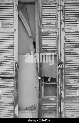 Brisée à bord de l'obturateur de fenêtre d'une vieille maison. Noir et blanc. Banque D'Images